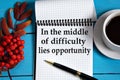 IN THE MIDDLE OF DIFFICULTY LIES OPPORTUNITY - words in a white notebook on a wooden blue background with a rowan branch and a Royalty Free Stock Photo
