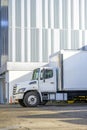 Middle duty day cab rig semi truck with box trailer for local business deliveries and moving standing on the city street parking