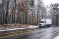 Middle duty white day cab rig semi truck with box trailer for local freight driving on the winter slippery road with snow and ice Royalty Free Stock Photo