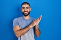 Middle east man with beard standing over blue background clapping and applauding happy and joyful, smiling proud hands together Royalty Free Stock Photo