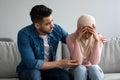 Middle-eastern man comforting his crying wife, home interior Royalty Free Stock Photo