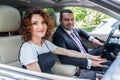 Middle Eastern man in a business suit with his curly-haired wife in a car