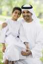 A Middle Eastern man and his son sitting in a park Royalty Free Stock Photo