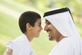 A Middle Eastern man and his son sitting in a park