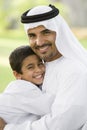 A Middle Eastern man and his son sitting in a park Royalty Free Stock Photo