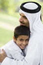 A Middle Eastern man and his son sitting in a park Royalty Free Stock Photo