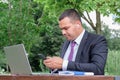 Middle eastern man sends text message on his smartphone. Serious young man in business suit and tie works