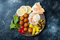 Middle Eastern meze platter with falafel, pita, hummus, pickles, radishes. Mediterranean or greek appetizer party idea.