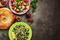 Middle Eastern salads tabbouleh and fattoush, pitta bread, pomegranate, figs on a dark rustic background. Arabic dishes, top view