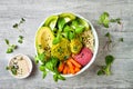 Middle eastern style Buddha bowl with green falafel, quinoa, butternut squash, tomatoes, avocado, beetroot hummus and tahini sauce