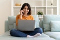 Middle Eastern Woman Using Laptop And Talking On Mobile Phone At Home Royalty Free Stock Photo