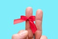 The middle finger of the left hand is decorated with a red bow on a light background, a gesture of two fingers.  Congratulations Royalty Free Stock Photo