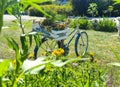 In the middle of the garden, with little yellow flowers, a bicycle painted blue and colorful flowers, with a white box, painted Royalty Free Stock Photo