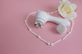 In the middle of the heart of the applicators is a face lift massager with attachments on a pink background Royalty Free Stock Photo