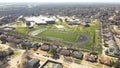 Middle school football stadium with artificial turf, yard markings, track and field situated in upscale residential neighborhood