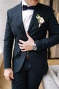 Middle selection of elegant groom in stylish dark blue suit with tie bow and boutonniere. Wedding day