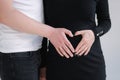 Middle selection on pregnant woman with her lovely husband puts their hands on her belly. Female in black bodycon dress Royalty Free Stock Photo