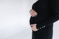 Middle selection on pregnant woman puts hands on her belly. Female in black bodycon dress. White background Royalty Free Stock Photo