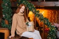 Middle shot portrait of smiling redhead young woman looking at camera happily holding gift in hand. Royalty Free Stock Photo