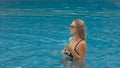 The wide middle shot pretty woman drinking blue cocktail alcohol liquor in swimming pool at hotel. Portrait of sexy girl Royalty Free Stock Photo