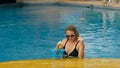 The wide middle shot pretty woman drinking blue cocktail alcohol liquor in swimming pool at hotel. Portrait of sexy girl