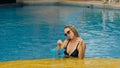 The wide middle shot pretty woman drinking blue cocktail alcohol liquor in swimming pool at hotel. Portrait of sexy girl Royalty Free Stock Photo