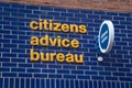 Citizens Advice Bureau sign in yellow and blue on brick wall Royalty Free Stock Photo