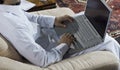 Mideastern man using laptop at home, with a cup of cofee and doc