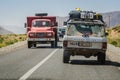 Midelt, Morocco - April 11, 2015. Fully loaded off road car on road trip passing by red vintage truck Royalty Free Stock Photo