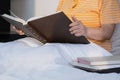 Midsection of adult obese woman is reading textbook on her bed in morning time