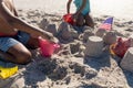 Midsection of african american brother and sister making sand castle together at beach on sunny day Royalty Free Stock Photo