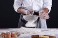 Midsection of african american male baker sieving flour on dough while standing