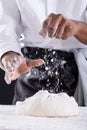 Midsection of african american male baker sprinkling flour on dough while kneading
