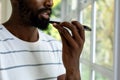 Midsection of african american man talking on smartphone and looking out window at home Royalty Free Stock Photo