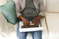 Midsection of african american man using laptop and sitting on couch in living room Royalty Free Stock Photo