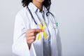 Midsection of african american mid adult female doctor holding yellow sarcoma awareness ribbon Royalty Free Stock Photo