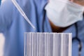 Midsection of african american mid adult female doctor wearing mask pipetting liquid in test tubes Royalty Free Stock Photo