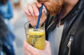 A midsection of man in outdoor cafe, drinking lemonade with a straw.