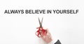 Midsection of businessman cutting the word Always believe in yourself on paper with scissors over gray background Royalty Free Stock Photo