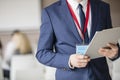 Midsection of businessman holding clipboard in seminar hall