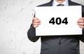 Midsection of businessman holding error 404 placard while standing against white brick wall Royalty Free Stock Photo