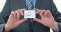 Midsection of businessman holding smiley face on card