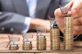 Businessman Placing Shopping Cart On Stacked Coins