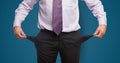 Midsection of businessman showing empty pockets against blue background