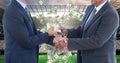 Midsection of businessmen exchanging money while shaking hands on soccer field representing corrupti Royalty Free Stock Photo