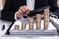 Businesswoman calculating invoice with stacked coins