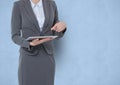 Midsection of businesswoman pointing at tablet PC over blue background