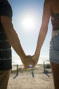 Midsection of caucasian couple on beach holiday holding hands