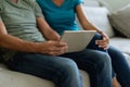 Midsection of caucasian couple sitting on couch using digital tablet Royalty Free Stock Photo