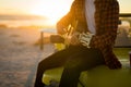 Midsection of caucasian man sitting on beach buggy by the sea playing guitar during sunset Royalty Free Stock Photo